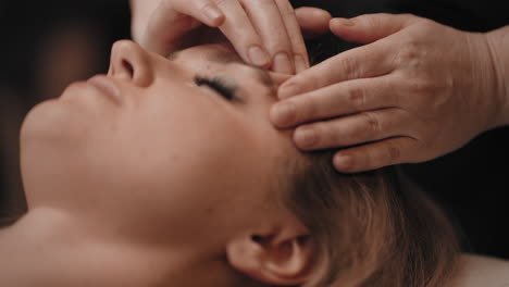 masseur-is-rubbing-temple-of-female-patient-healing-headache-by-massage-relax-in-spa-salon-facial-massage